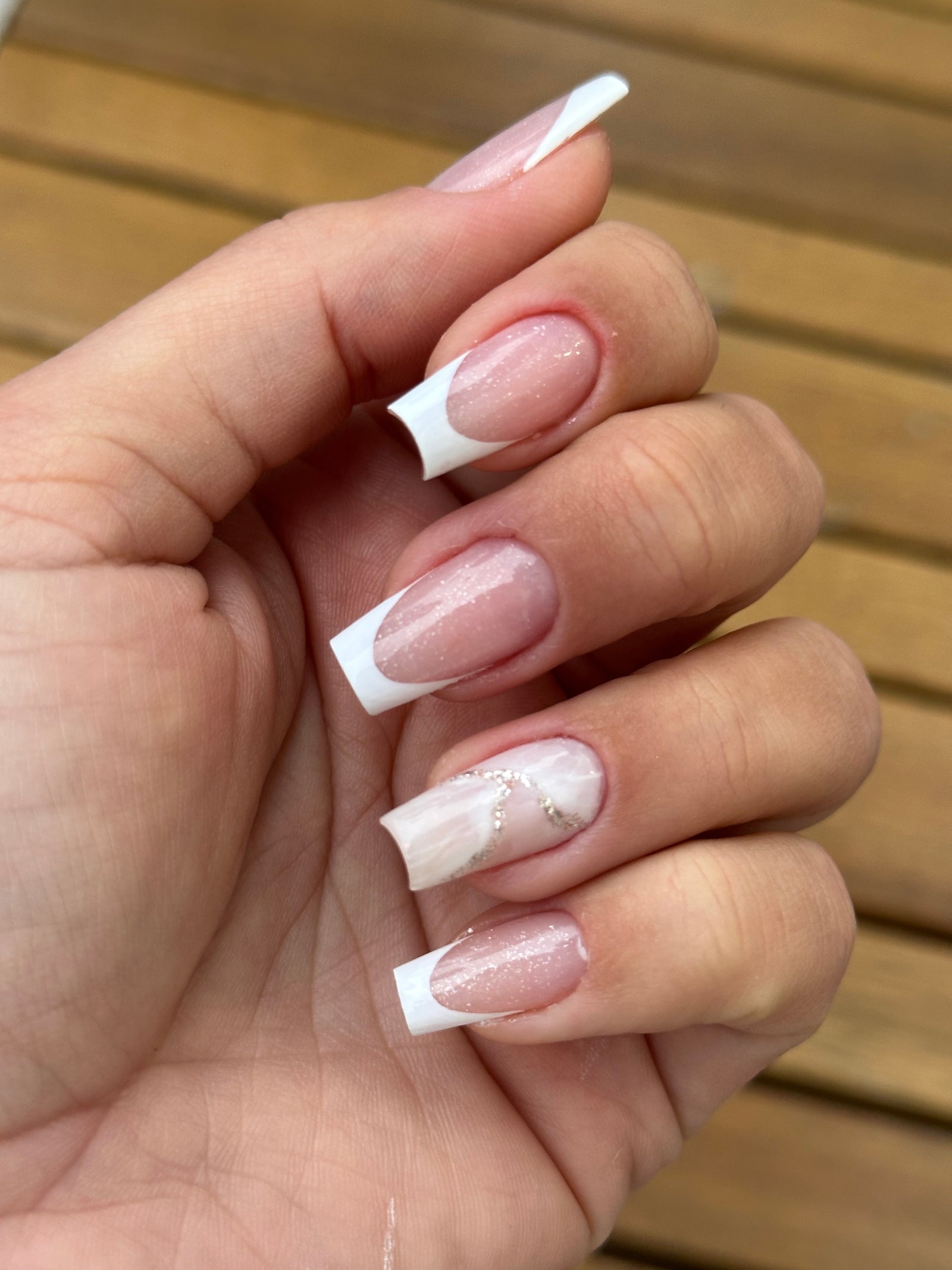 Witte French tips met een gemarmerd accent op een houten ondergrond