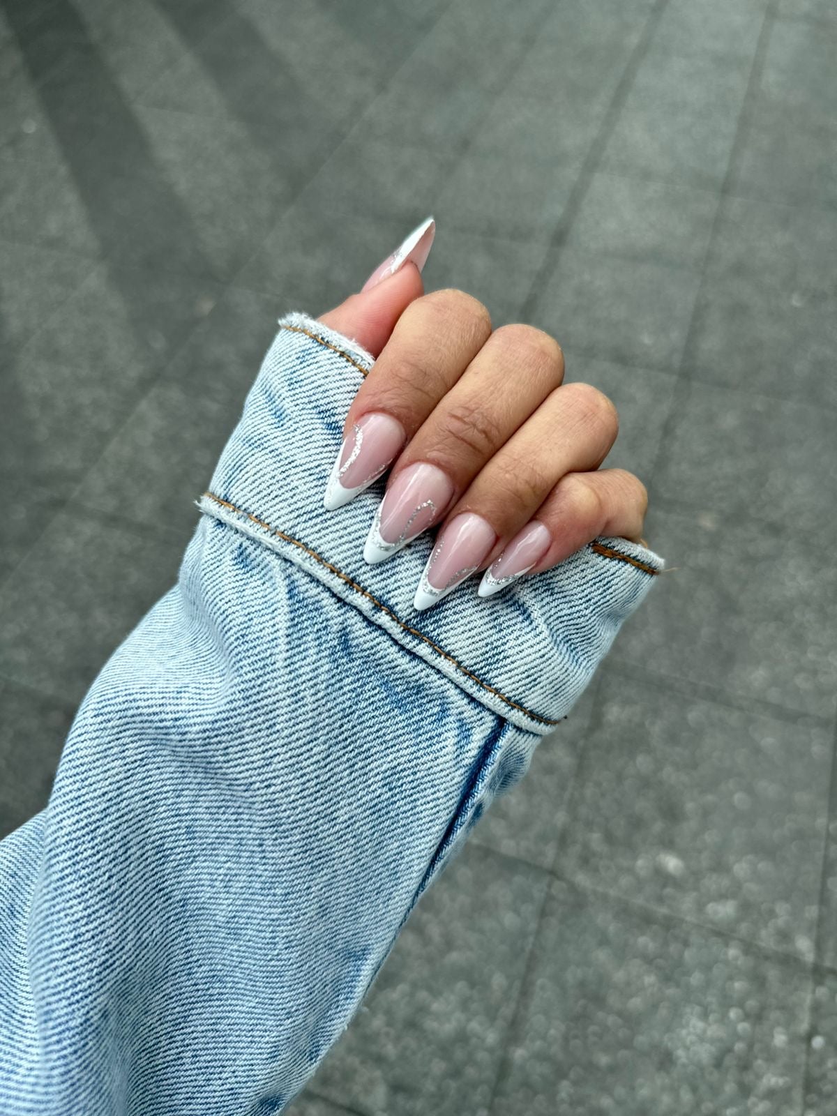 Amandelvormige French nagels, hand in een spijkerjasje