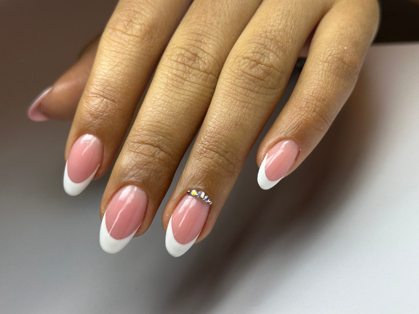 Amandel French nagels met een kristal op de ringvinger